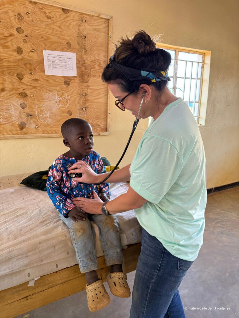 A Fraternity Without Borders caravan volunteer caring for a child in Dzaleka, Malawi