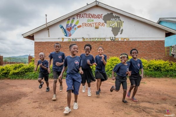Ubuntu Nation School pupils running in front of the school mural, “I am because we are”