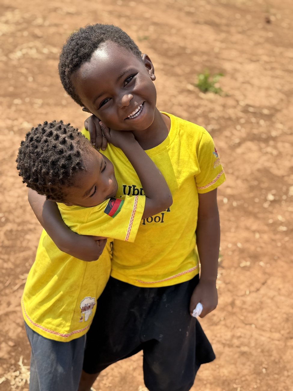 Two Ubuntu Nation School pupils hugging and smiling